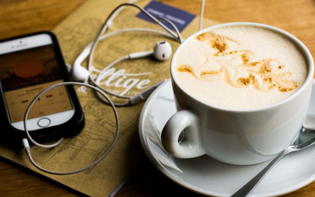 A phone with headphones playing a podcast influenced by AI technology, next to a cup of coffee